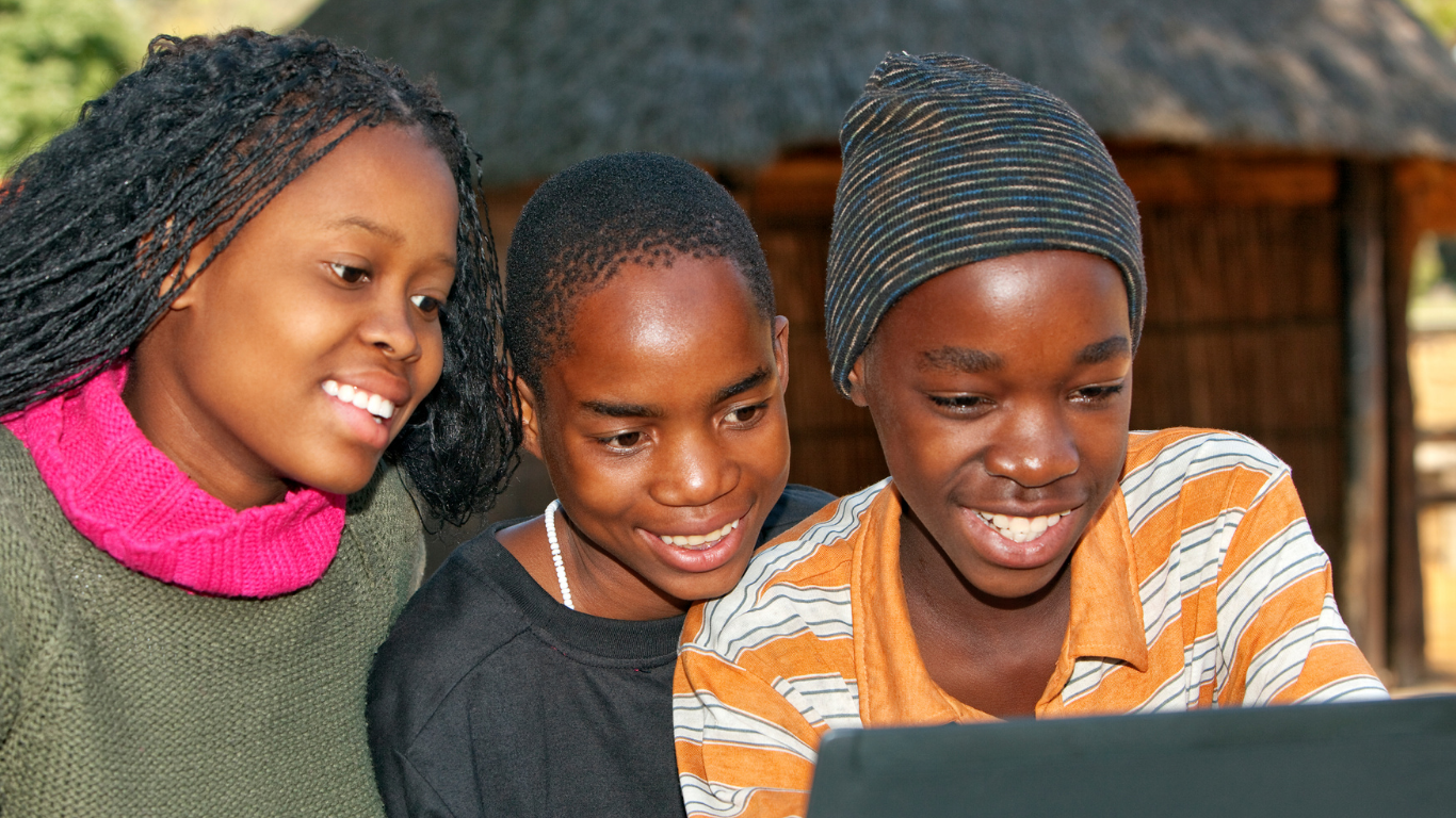 Students and a teacher at a laptop